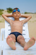 © alexeytsurkan - Young guy in swimming glasses is sunbathing on a sunbed on the sea beach.