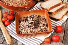 Buckwheat Porridge With Mushrooms In Ceramic Pot On Table
