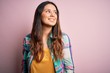 © Krakenimages.com - Young beautiful brunette woman wearing casual colorful shirt standing over pink background looking away to side with smile on face, natural expression. Laughing confident.