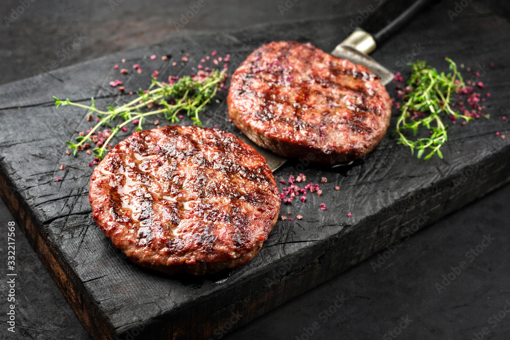 Barbecue Wagyu Hamburger with red wine salt and herbs as closeup on a charred wooden board - obrazy, fototapety, plakaty 