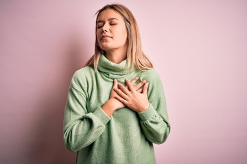 Poster - Young beautiful blonde woman wearing winter wool sweater over pink isolated background smiling with hands on chest with closed eyes and grateful gesture on face. Health concept.