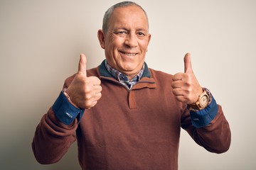 Senior handsome man  wearing elegant sweater standing over isolated white background success sign doing positive gesture with hand, thumbs up smiling and happy. Cheerful expression and winner gesture.