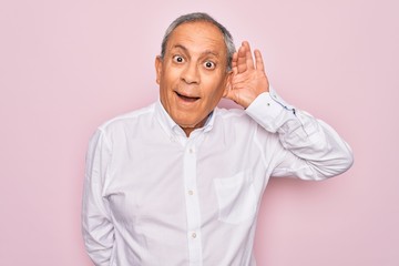 Sticker - Senior handsome grey-haired man wearing elegant shirt over isolated pink background smiling with hand over ear listening an hearing to rumor or gossip. Deafness concept.