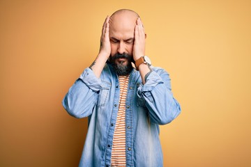 Sticker - Handsome bald man with beard wearing casual denim jacket and striped t-shirt suffering from headache desperate and stressed because pain and migraine. Hands on head.