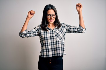 Young brunette woman with blue eyes wearing casual shirt and glasses over white background Dancing happy and cheerful, smiling moving casual and confident listening to music