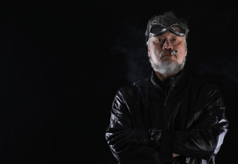 Wall Mural - studio portrait of an old biker with a cigar on a black background