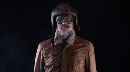 Poster - studio portrait of an old biker with a cigar on a black background