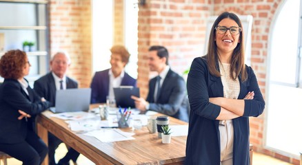 Group of business workers smiling happy and confident working together in a meeting. One of them, standing with smile on face looking at camera at the office.