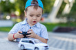 a small boy plays with a toy car on radio control holding a remote control