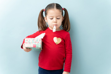 Wall Mural - Portrait of a cute little girl with ponytails checking her temperature with a termometer