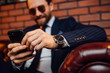 © Тарас Нагирняк - Croppedimage, bearded man wearing  suit sitting on the leather sofa holding smartphone. Comfort and relaxation.