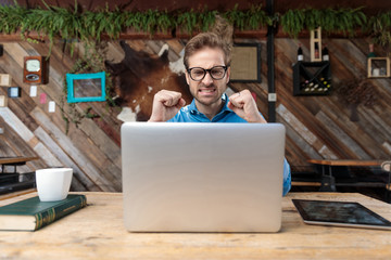 Wall Mural - businessman sitting at desk and looking at laptop angry