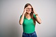 © Krakenimages.com - Young beautiful redhead woman wearing casual green t-shirt and glasses over white background with hand on headache because stress. Suffering migraine.