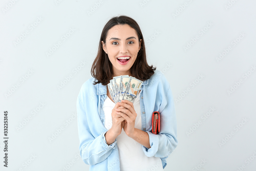 Young woman with wallet and money on light background