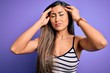 © Krakenimages.com - Young beautiful woman wearing casual summer striped top over purple isolated background suffering from headache desperate and stressed because pain and migraine. Hands on head.