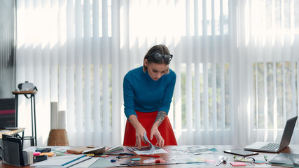 Wall Mural - working on a new project. young female designer in casual wear analyzing some documents while standi