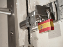 A Bolted Door Secured By A Padlock With The National Flag Of Spain On It.(series)