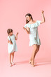 © Pixel-Shot - Happy mother and her little daughter dancing against color background