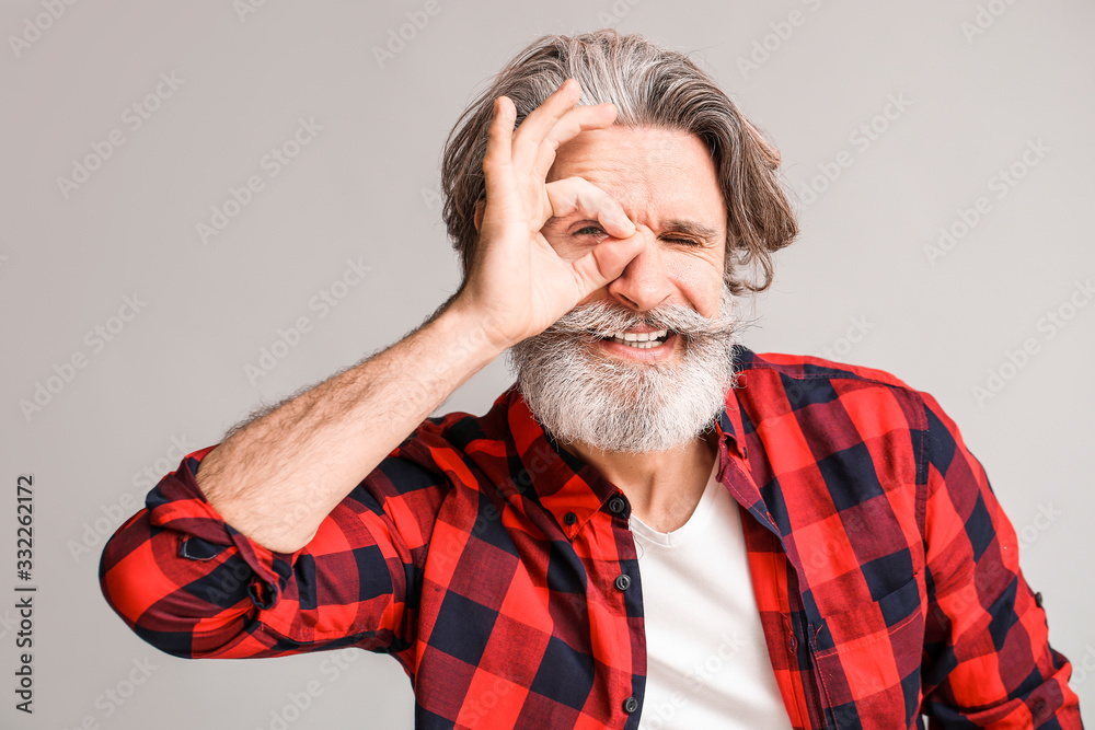 Stylish elderly man showing OK gesture on grey background