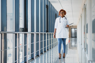 Pretty young African American medical professional standing and looking at camera in a hospital.