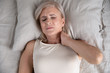 © fizkes - Top above view head shot close up older unhappy woman lying in bed, waking up in morning, feeling strong neck ache. Stressed middle aged lady suffering from painful feelings after uncomfortable sleep.
