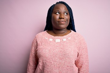 Poster - African american plus size woman with braids wearing casual sweater over pink background smiling looking to the side and staring away thinking.