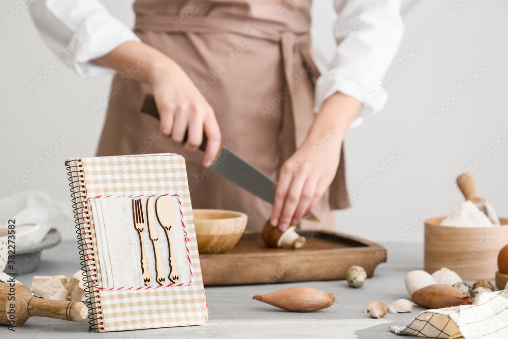 Woman with cook book preparing food in kitchen - obrazy, fototapety, plakaty 