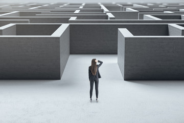 Poster - Businesswoman standing at entrance to a concrete labyrinth.