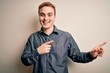 © Krakenimages.com - Young handsome redhead man wearing casual shirt standing over isolated white background smiling and looking at the camera pointing with two hands and fingers to the side.