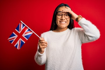 Canvas Print - Young asian woman holding united kingdom flag for brexit referendum over red background stressed with hand on head, shocked with shame and surprise face, angry and frustrated. Fear and upset