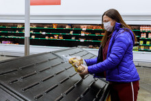 Woman With Face Mask Holding Last Bag Of Potato At Supermarket With Empty Shelves.