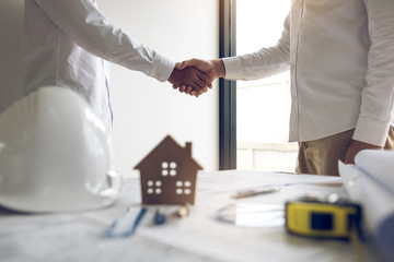 Wall Mural - Two partnership engineering man with construction worker greeting shaking hand a foreman at renovating apartment.