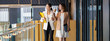 © THANANIT - Banner, web page or cover template of Two asian businesswomen walking and talking during coffee break in modern office or coworking space, relaxing and talking, business and people partnership concept