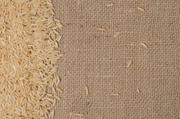 unpolished rice grains on a background of rough burlap. A diet rich in vitamins and nutrients.