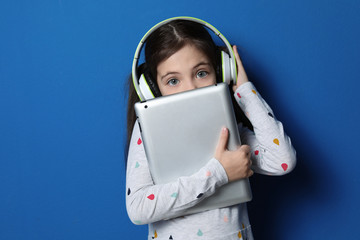 Sticker - Cute little girl with headphones and tablet listening to audiobook on blue background