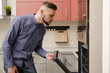 © Oleg - attractive bearded man peeks into an oven in a modern kitchen