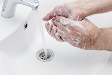 Wall Mural - Coronavirus prevention washing hands with antibacterial soap at bathroom sink man hand hygiene.