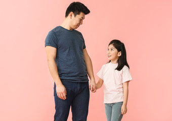 Wall Mural - Happy Asian man and his little daughter on color background