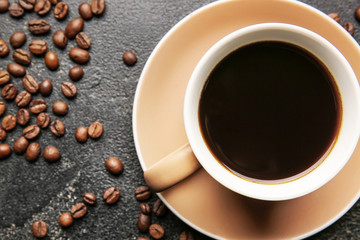 Cup of hot coffee and beans on dark background