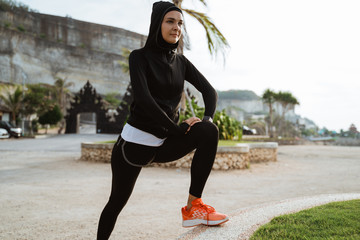 Wall Mural - muslim female workout before fitness training session outdoor. Healthy young woman warming up outdoors