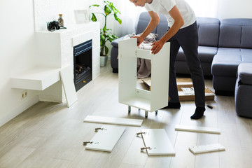 young man putting self assembly furniture as they move into your new house.