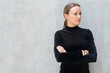 © Ranta Images - Beautiful blonde businesswoman thinking with arms crossed against concrete wall