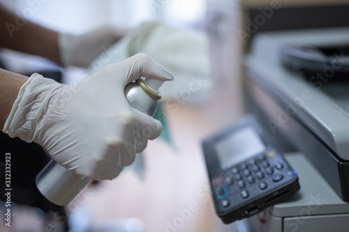Fotomural Woman disinfects a printer and a photocopier in the office with a spray disinfectant liquid