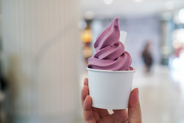 Wall Mural - Purple Sweet Potato ice cream soft serve. Woman holding a cup of soft serve ice cream with yogurt sweet potato flavour. (isolated)