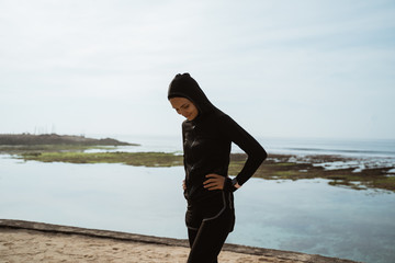 Wall Mural - Fitness sport muslim girl resting after intensive run, young attractive runner taking break after jogging outdoors