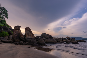 mossy green rocks at the beach of agonda at sunset in goa, india