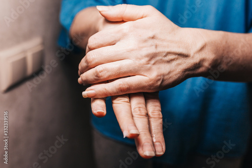 Fotografía Woman lubricates tired and dry hands from frequent washing with moisturizer