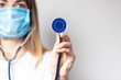 female doctor in a medical mask holds a stethoscope on a light background. Added flag of Europe. Concept medicine, level of medicine, virus, epidemic