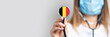 female doctor holding a stethoscope on a light background. Added flag of Belgium. Concept medicine, level of medicine, virus, epidemic. Baner