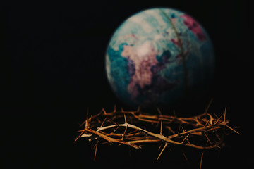 Close up of crown of thorns of Jesus over blurred world globe on black background can be used for Christian concept , Easter concept with copy space